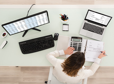 Woman at desk with computer and laptop