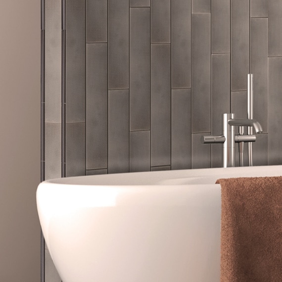 Standalone bathtub and brushed nickel fixtures in front of 3x18 pewter metal wall tile.