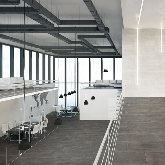 Corporate office with gray concrete tile flooring, off-white concrete wall tile, black conference tables & white chairs, and floor-to-ceiling windows.