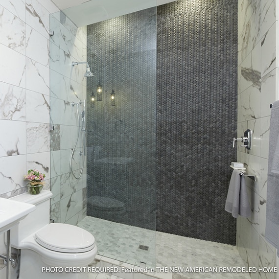 Bathroom with white & gray wall and floor tile that looks like marble, large walk-in shower with black basketweave feature wall, and gray marble mosaic floor tile.