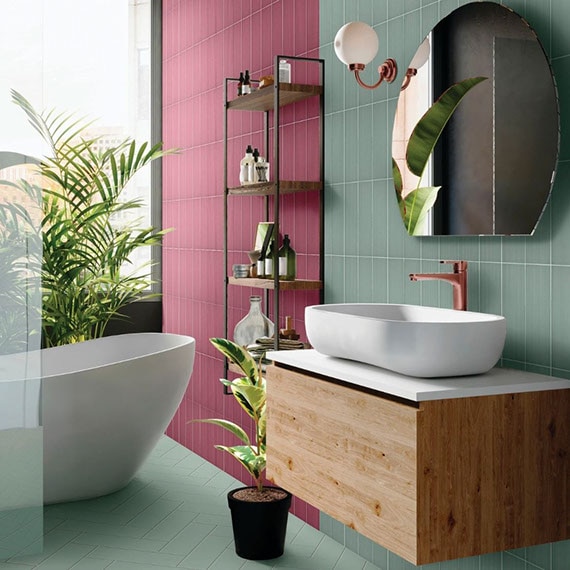 Colorful bathroom with light green tile flooring laid in a herringbone pattern, light green & maroon backsplash, floating wood vanity with vessel sink.
