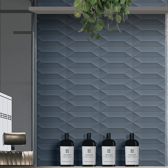 Barber shop with blue textured wall tile and gray wood countertop holding rolled towels.