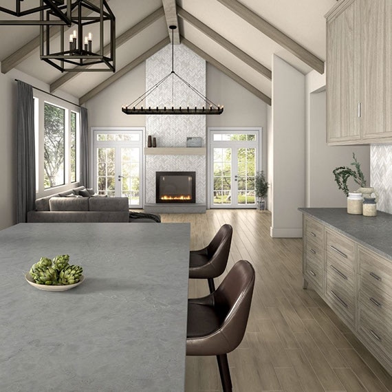 Great room open to the kitchen with vaulted ceiling, fireplace with gray tile, tile flooring that looks like wood, gray kitchen island and countertops.