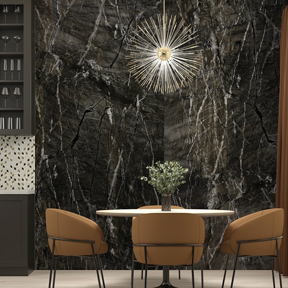 Dining room with stunning walls of black granite slab with white veining, and starburst lighting over table with four tan leather chairs.